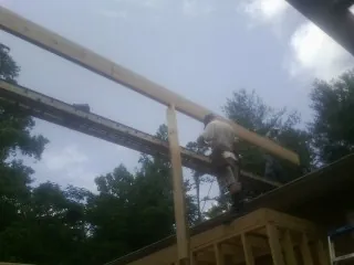 Carpenter setting a ridge beam over a new addition frame — Ice Dam Removal by Roofing Brothers in Battleboro