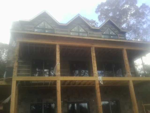 Dormers and porch framing on a large log home under construction — Roof Coating work by our crew in Battleboro