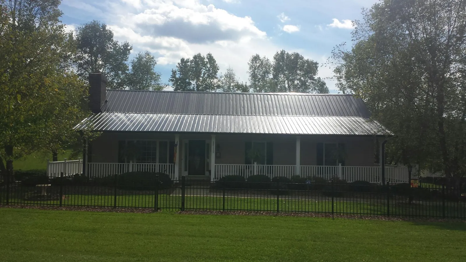 Gray metal roof on a brick ranch with a full width front porch — Gutter Guard Installation work by our crew in Battleboro