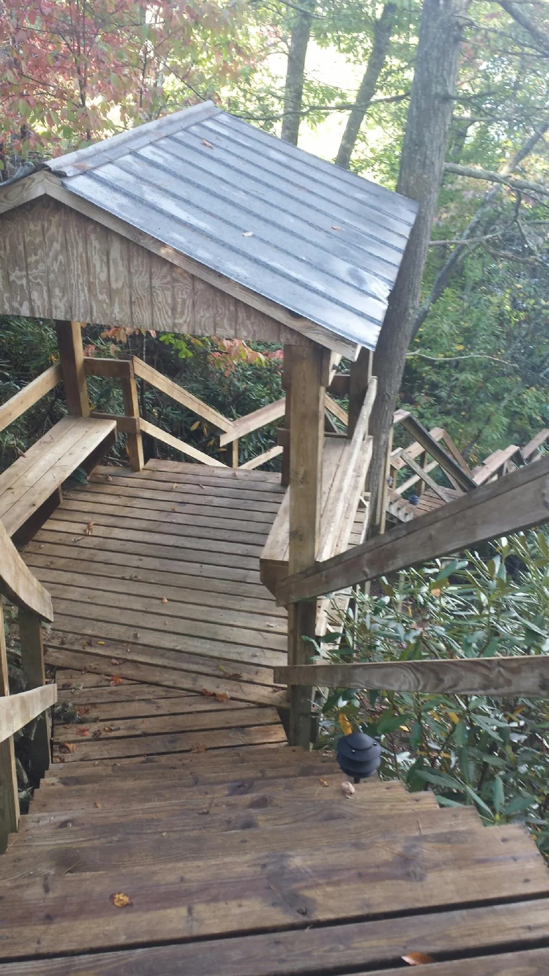 Metal roofed shelter over wooden steps on a wooded walkway — Skylight Repair & Installation work by our crew in Battleboro