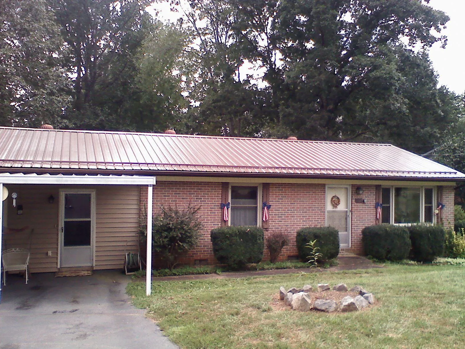 Bronze metal roof and carport on a brick ranch home — Roof Repair work by our crew in Battleboro