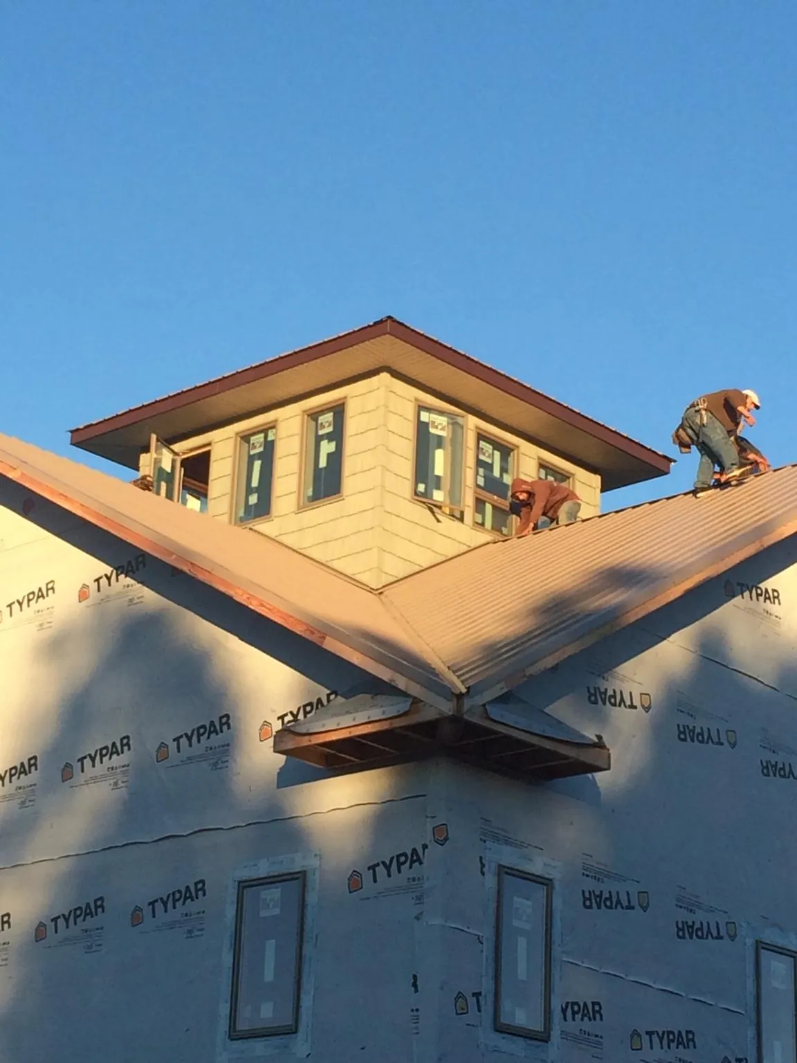 Roofers working around a rooftop cupola on a new metal roof at sunset — Roof Waterproofing in Battleboro by Roofing Brothers